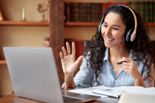 Woman smiling and working on laptop with headset